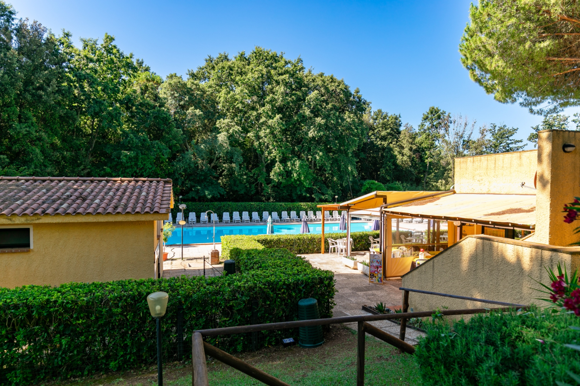 La piscina del Residence il Paradiso circondata dal prato verde, alberi e siepi