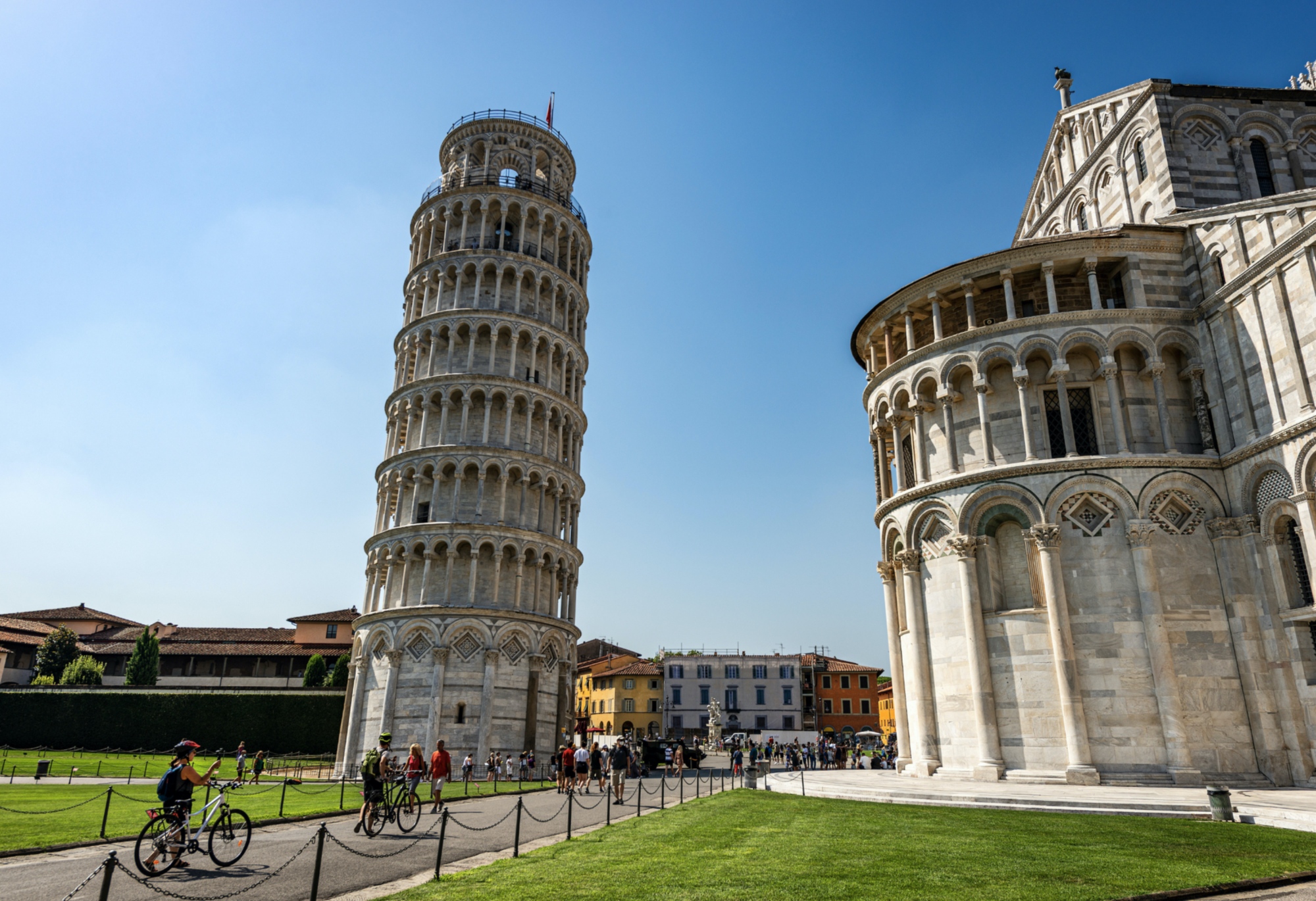 Ciclisti davanti alla Torre Pendente di Pisa e alla facciata del Duomo in Piazza dei Miracoli