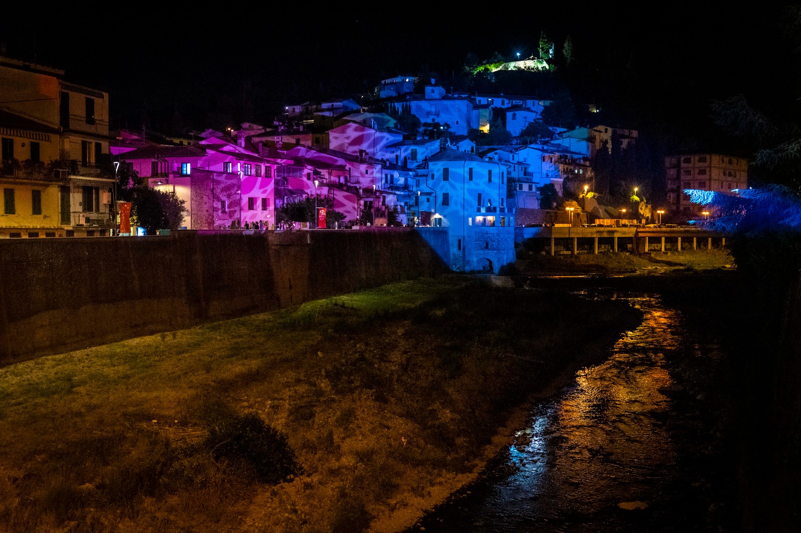 Photo de Montelupo Fiorentino prise de nuit, éclairée par les lumières colorées de ses bâtiments historiques.