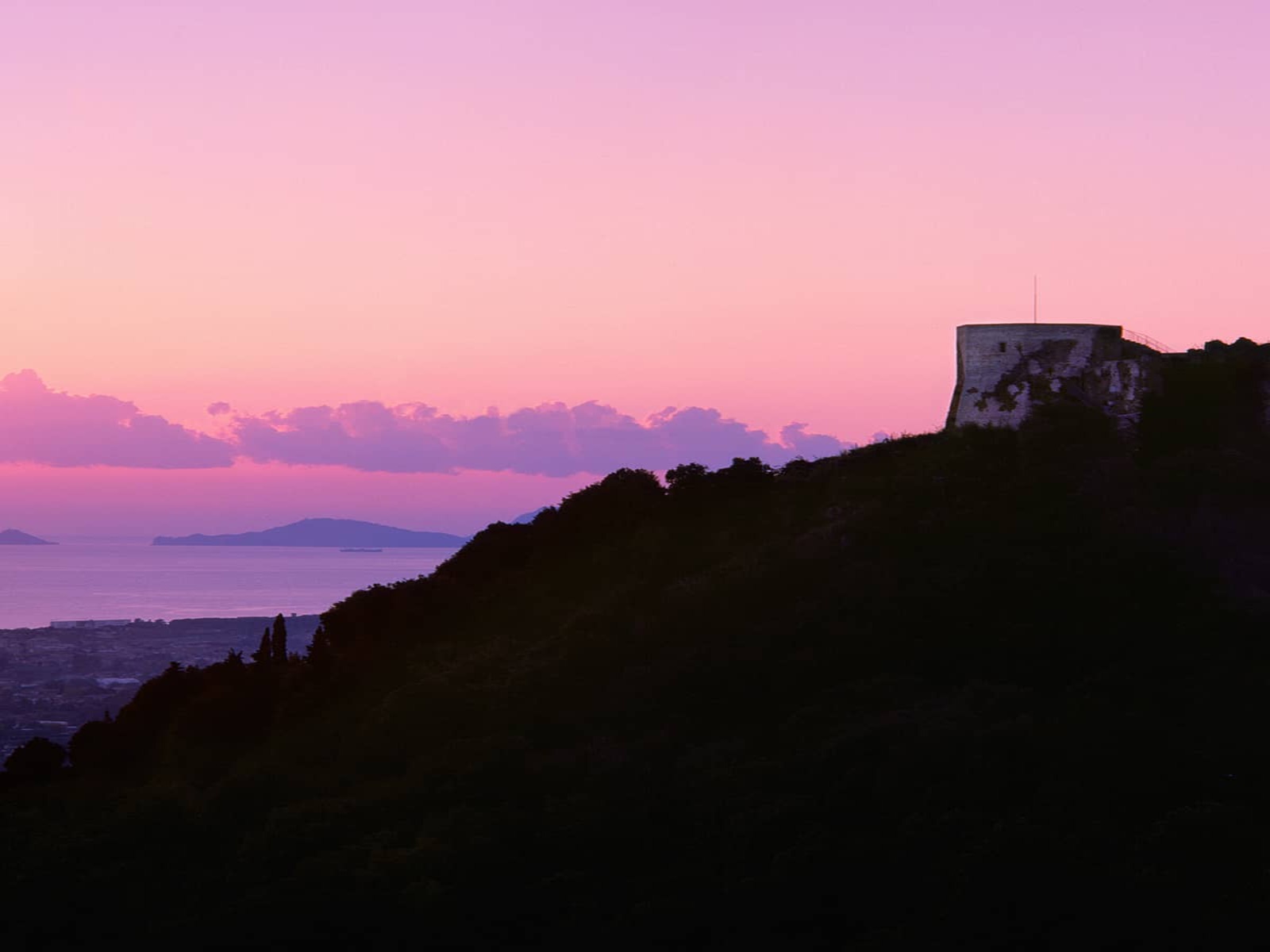 Vue du château d’Aghinolfi au coucher du soleil, avec la mer en arrière-plan.