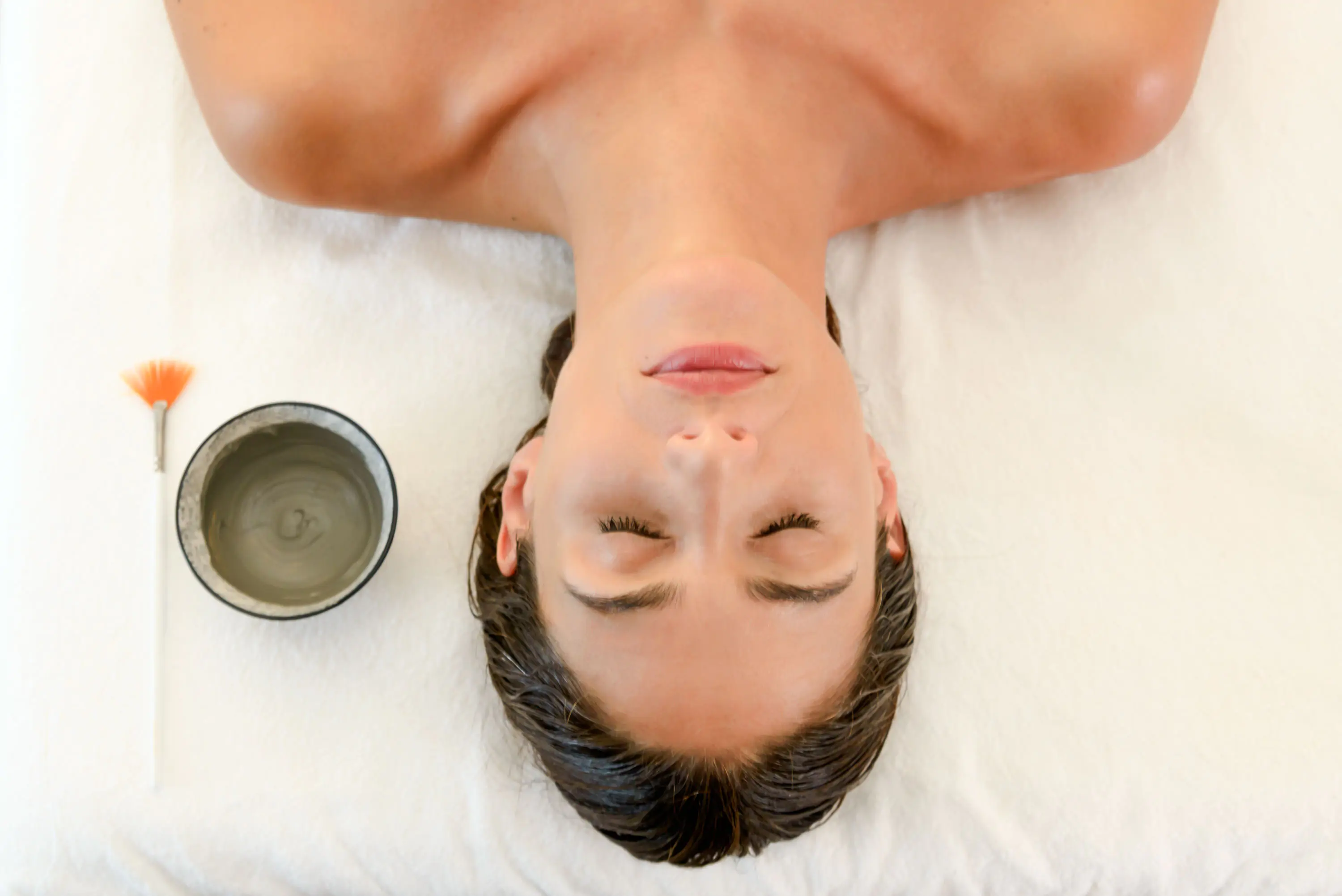 Femme allongée effectuant un soin du visage.