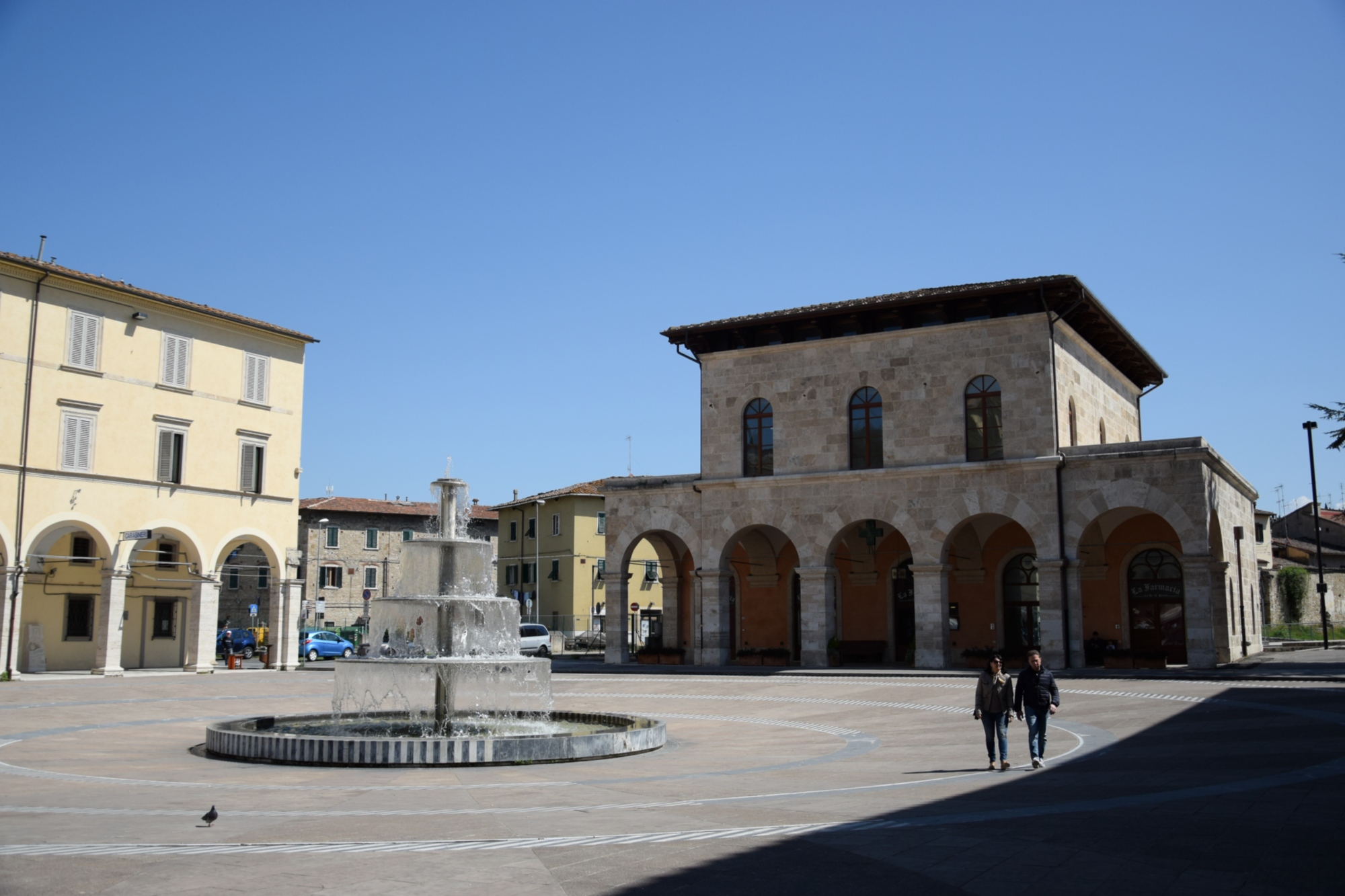 Gare de Colle Val d’Elsa avec une fontaine et deux passants
