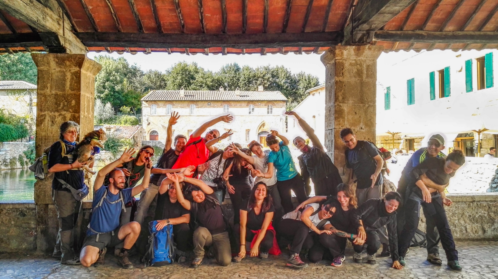 Groupe de pèlerins posant devant la piscine thermale historique de Bagno Vignoni.