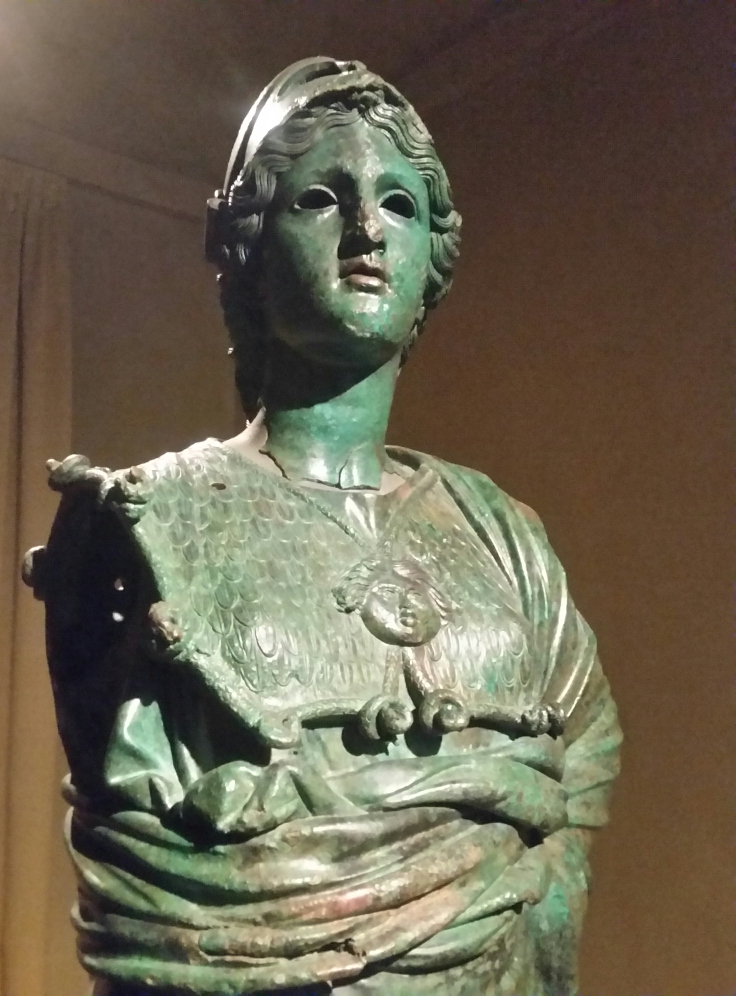 Statue étrusque en bronze connue sous le nom de Minerve d’Arezzo, représentant la déesse armée d’un casque et d’un bouclier, symbole de sagesse et de protection, conservée au Musée archéologique national de Florence.