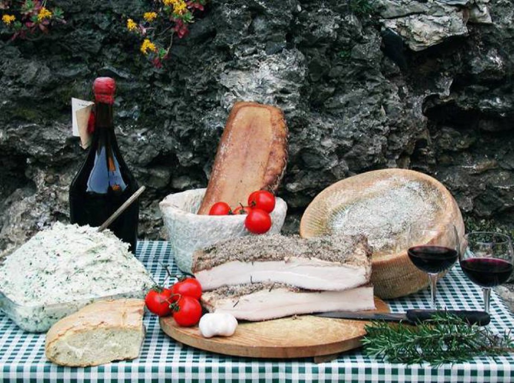 Table dressée avec fromage, pain, lard de Colonnata et verres de vin rouge